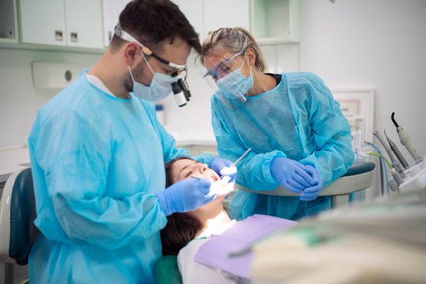 a dentist and dental assistant performing a dental treatment to a patient